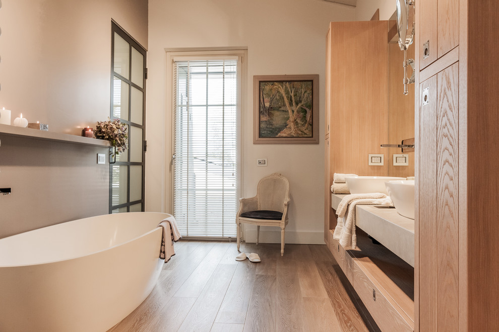 Cette image montre une salle de bain principale rustique en bois brun de taille moyenne avec un placard à porte plane, une baignoire indépendante, un mur beige, un sol en bois brun, une vasque, un plan de toilette en bois, un sol marron et un plan de toilette beige.