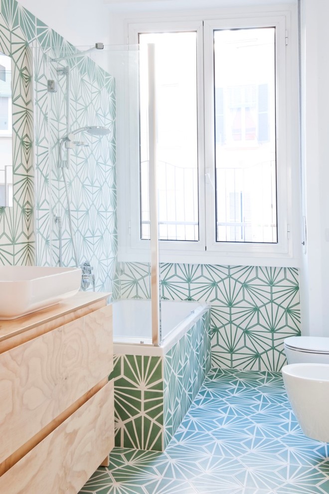 Small eclectic ensuite bathroom in Milan with beaded cabinets, light wood cabinets, a corner bath, green tiles, cement tiles, green walls, cement flooring, a vessel sink, wooden worktops, green floors and a hinged door.