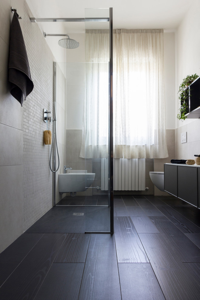 Foto på ett mellanstort funkis vit badrum med dusch, med luckor med infälld panel, grå skåp, en kantlös dusch, en vägghängd toalettstol, beige kakel, porslinskakel, vita väggar, klinkergolv i porslin, ett väggmonterat handfat, bänkskiva i glas, svart golv och med dusch som är öppen