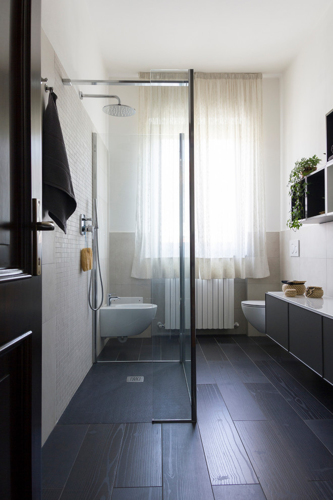 Источник вдохновения для домашнего уюта: ванная комната среднего размера в современном стиле с фасадами с утопленной филенкой, серыми фасадами, душем без бортиков, инсталляцией, бежевой плиткой, керамогранитной плиткой, белыми стенами, полом из керамогранита, душевой кабиной, подвесной раковиной, стеклянной столешницей, черным полом, открытым душем и белой столешницей