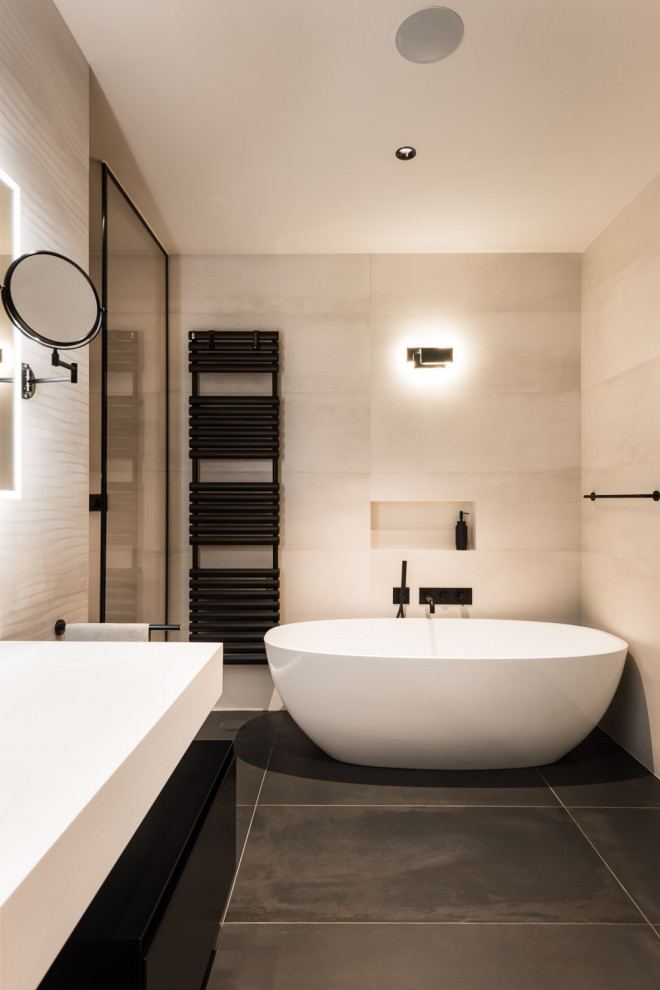 Пример оригинального дизайна: большая главная ванная комната в стиле модернизм с отдельно стоящей ванной, душем в нише, раздельным унитазом, бежевой плиткой, керамогранитной плиткой, бежевыми стенами, монолитной раковиной, черным полом, душем с распашными дверями, белой столешницей, тумбой под одну раковину и подвесной тумбой