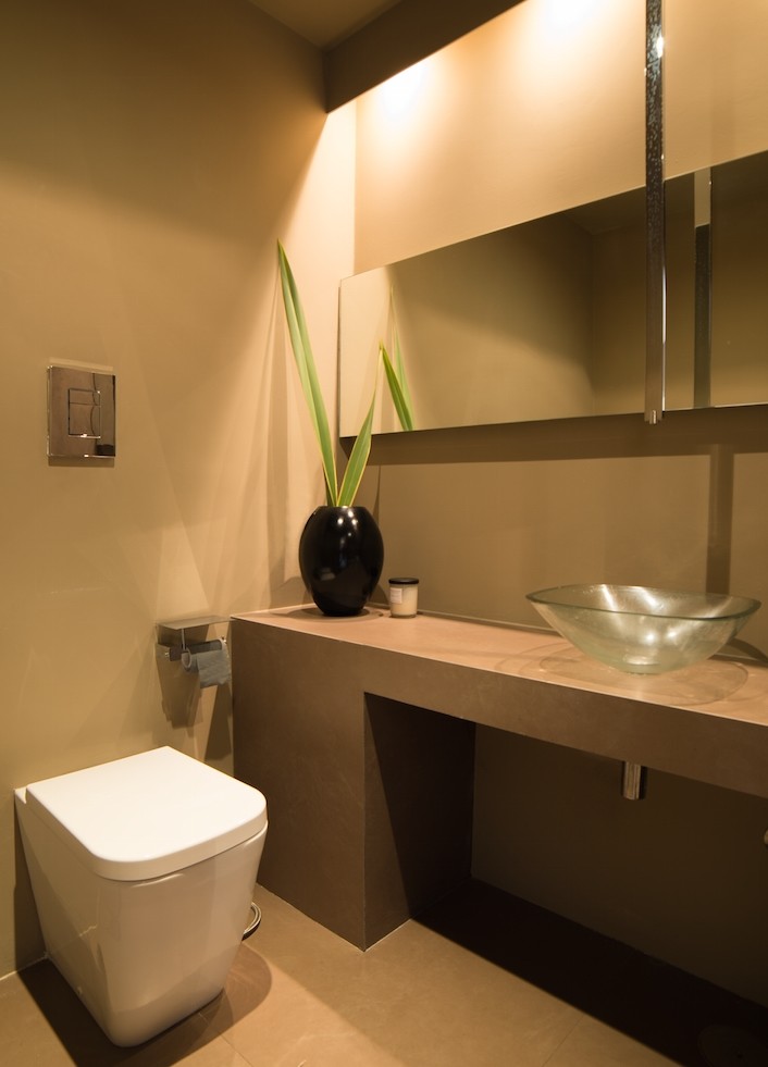 Idée de décoration pour un petit WC et toilettes design avec des portes de placard beiges, WC séparés, un carrelage beige, des carreaux de porcelaine, un mur marron, un sol en carrelage de porcelaine, une vasque et un plan de toilette en béton.