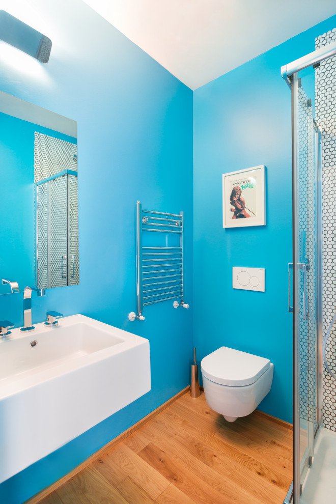 Пример оригинального дизайна: маленькая ванная комната в современном стиле с светлыми деревянными фасадами, раздельным унитазом, белой плиткой, плиткой мозаикой, синими стенами, деревянным полом, душевой кабиной, настольной раковиной, душем с распашными дверями, белой столешницей, нишей, тумбой под одну раковину и подвесной тумбой для на участке и в саду