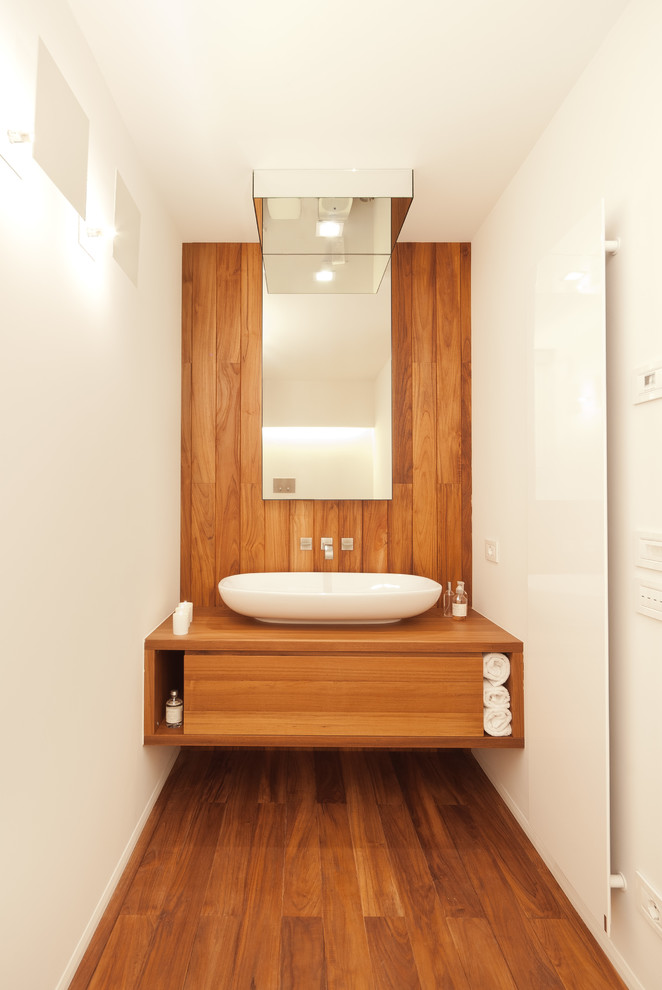 Diseño de cuarto de baño contemporáneo con lavabo sobreencimera, armarios con paneles lisos, puertas de armario de madera oscura, encimera de madera, paredes blancas y suelo de madera en tonos medios