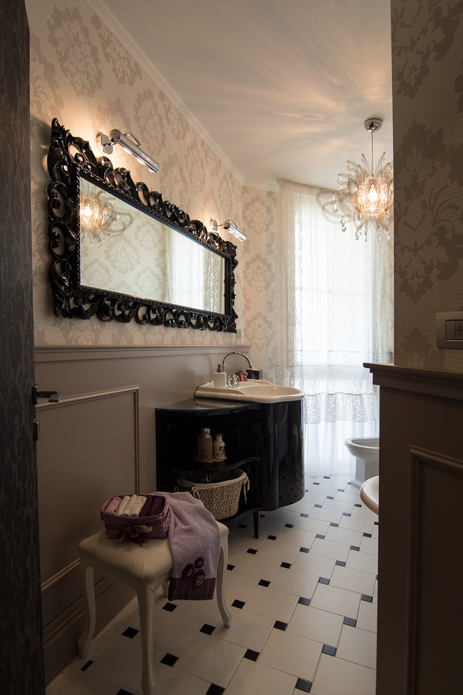 Bild på ett litet funkis badrum, med öppna hyllor, svarta skåp, ett badkar med tassar, en toalettstol med separat cisternkåpa, svart och vit kakel, keramikplattor, beige väggar, klinkergolv i keramik, ett konsol handfat och bänkskiva i glas