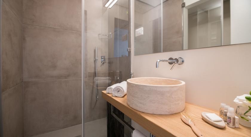Modelo de cuarto de baño minimalista con puertas de armario de madera clara, ducha a ras de suelo, aseo y ducha y encimera de madera