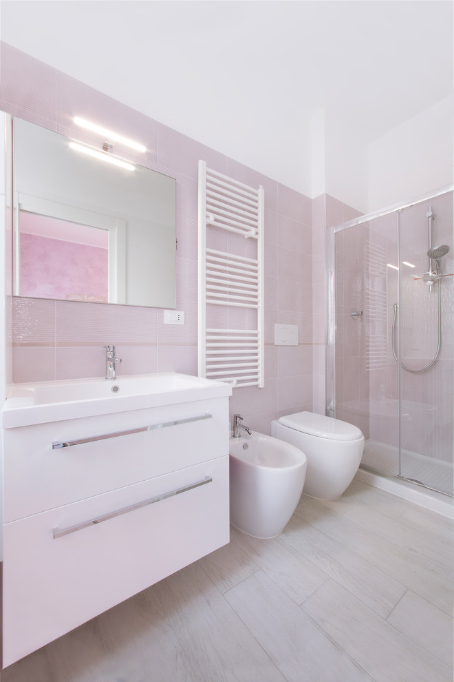 Foto di una stanza da bagno con doccia costiera di medie dimensioni con ante lisce, ante bianche, doccia alcova, bidè, piastrelle rosa, piastrelle in ceramica, pareti bianche e lavabo da incasso