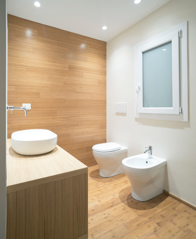 Exempel på ett litet minimalistiskt badrum med dusch, med öppna hyllor, skåp i ljust trä, en dusch i en alkov, en toalettstol med separat cisternkåpa, vit kakel, porslinskakel, vita väggar, bambugolv, ett fristående handfat, träbänkskiva, brunt golv och med dusch som är öppen