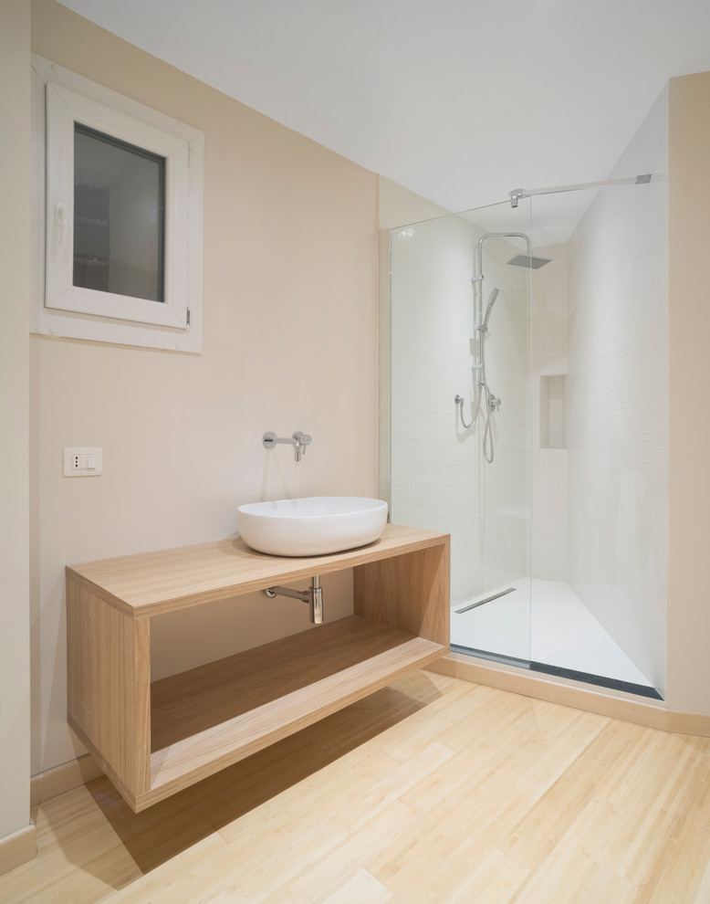 Bild på ett litet minimalistiskt badrum med dusch, med öppna hyllor, skåp i ljust trä, en dusch i en alkov, en toalettstol med separat cisternkåpa, vit kakel, porslinskakel, beige väggar, bambugolv, ett fristående handfat, träbänkskiva, brunt golv och med dusch som är öppen