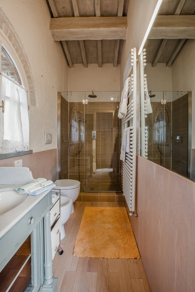 Idéer för att renovera ett mellanstort medelhavsstil badrum med dusch, med öppna hyllor, en dusch i en alkov, beige väggar, blå skåp, en bidé, brun kakel, ljust trägolv, ett undermonterad handfat, brunt golv och dusch med gångjärnsdörr