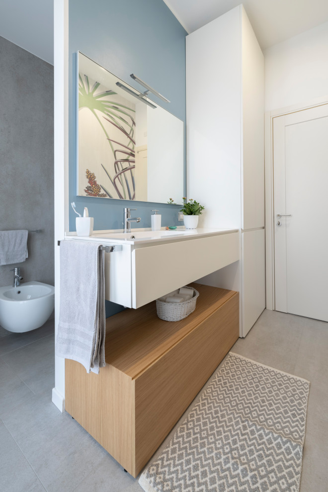 Design ideas for a medium sized contemporary shower room bathroom in Milan with flat-panel cabinets, white cabinets, grey tiles, porcelain tiles, porcelain flooring, an integrated sink, engineered stone worktops, grey floors, white worktops, a wall mounted toilet, blue walls, a single sink and a floating vanity unit.
