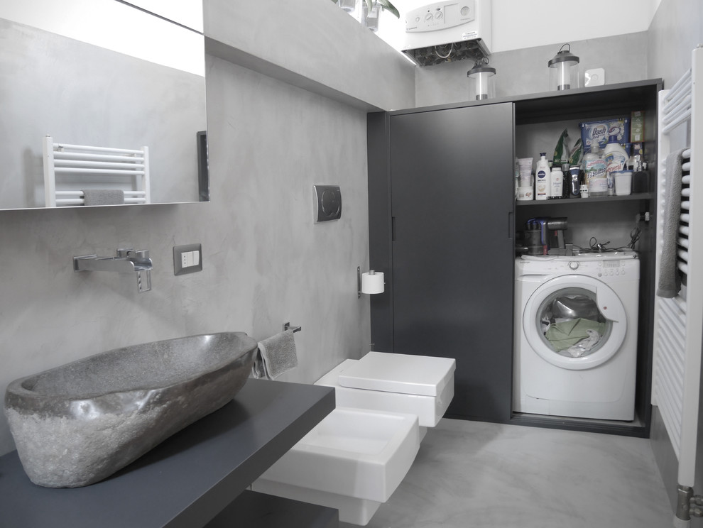 Foto på ett mellanstort funkis grå badrum med dusch, med släta luckor, grå skåp, en dusch i en alkov, en vägghängd toalettstol, grå kakel, grå väggar, betonggolv, ett fristående handfat, träbänkskiva, grått golv och dusch med skjutdörr