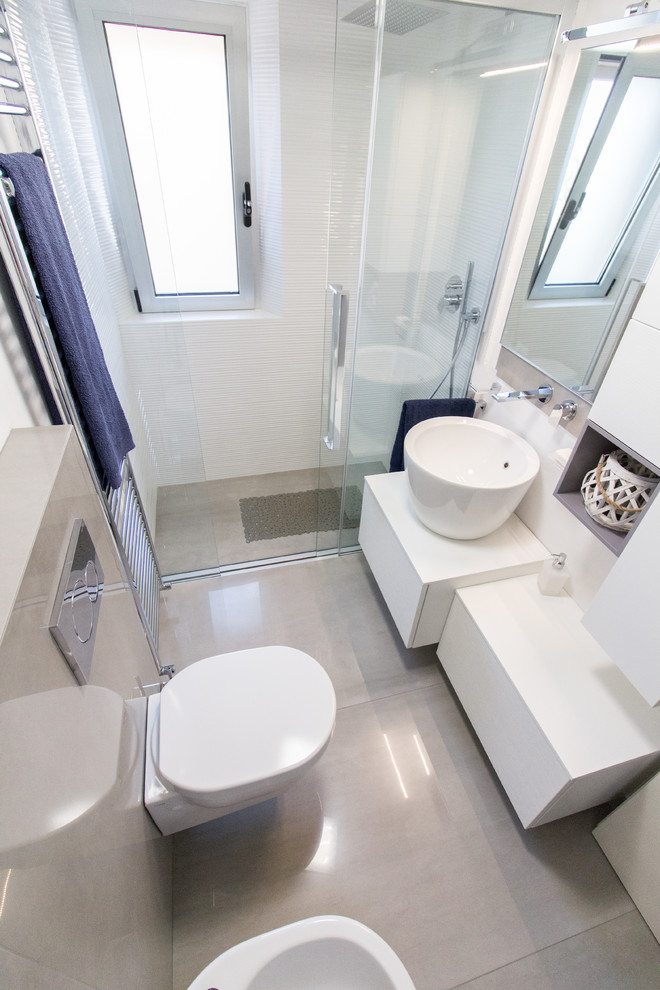 Idéer för små funkis badrum med dusch, med släta luckor, vita skåp, en kantlös dusch, en vägghängd toalettstol, vit kakel, porslinskakel, vita väggar, klinkergolv i porslin, ett fristående handfat, grått golv, dusch med skjutdörr och träbänkskiva