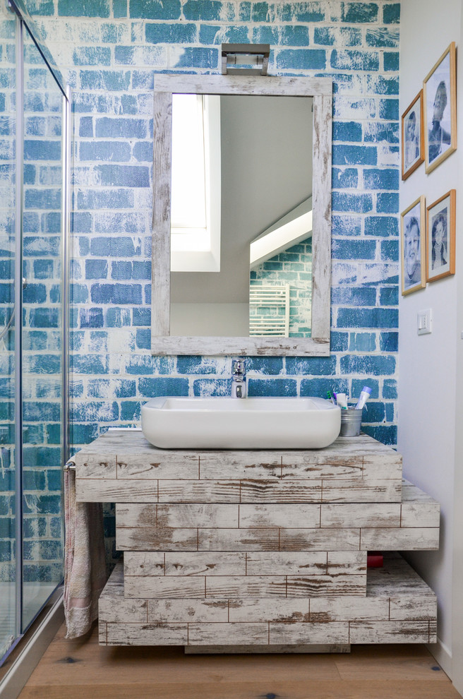 Esempio di una piccola stanza da bagno con doccia shabby-chic style con ante lisce, ante in legno chiaro, doccia ad angolo, WC sospeso, pareti blu, parquet chiaro, lavabo a bacinella e top in laminato