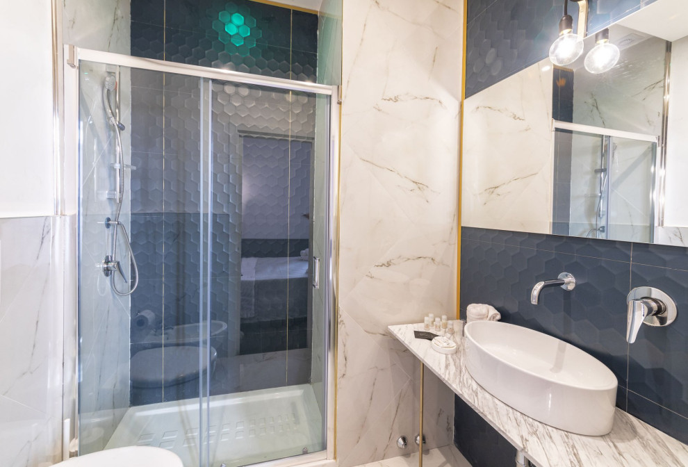 Eklektisk inredning av ett litet vit vitt badrum med dusch, med en dusch i en alkov, en vägghängd toalettstol, blå kakel, porslinskakel, vita väggar, klinkergolv i porslin, ett fristående handfat, marmorbänkskiva, vitt golv och dusch med skjutdörr