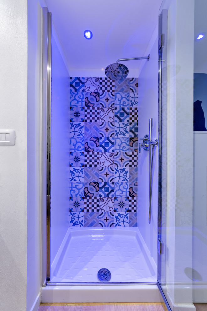 Modern inredning av ett litet badrum med dusch, med vita skåp, en dusch i en alkov, en toalettstol med separat cisternkåpa, flerfärgad kakel, porslinskakel, vita väggar, ljust trägolv, ett fristående handfat, träbänkskiva, beiget golv och dusch med gångjärnsdörr