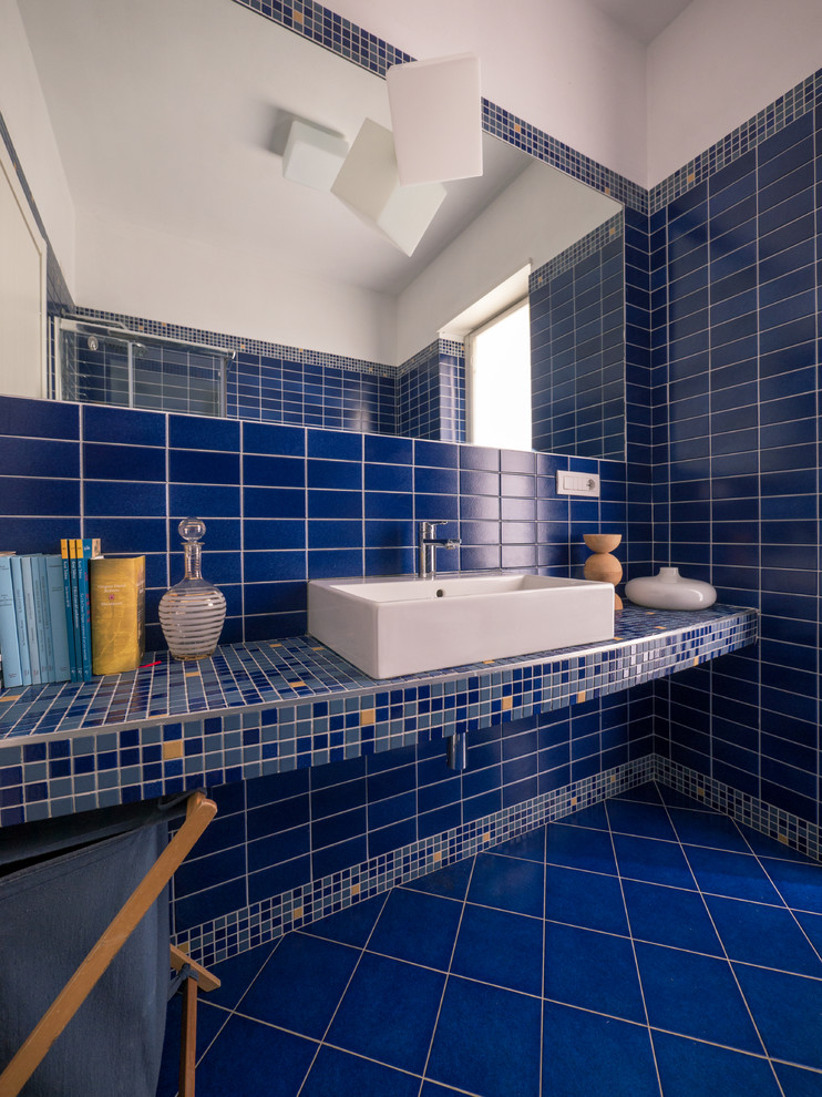 Foto på ett litet funkis badrum med dusch, med en hörndusch, en toalettstol med separat cisternkåpa, blå kakel, mosaik, blå väggar, klinkergolv i keramik, ett avlångt handfat, bänkskiva i betong, blått golv och dusch med skjutdörr