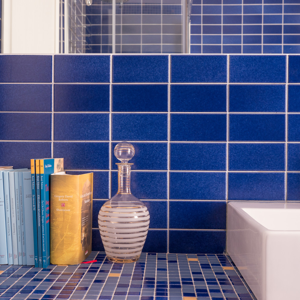 Bild på ett litet funkis badrum med dusch, med en hörndusch, en toalettstol med separat cisternkåpa, blå kakel, mosaik, blå väggar, klinkergolv i keramik, ett avlångt handfat, bänkskiva i betong, blått golv och dusch med skjutdörr