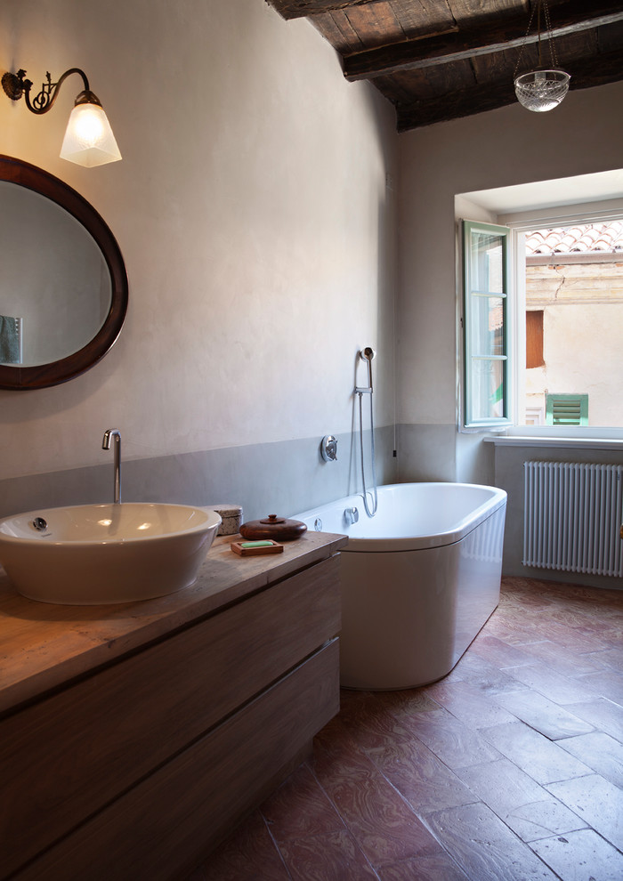 Bild på ett stort lantligt en-suite badrum, med en jacuzzi, en dusch i en alkov, grå väggar, tegelgolv, ett fristående handfat, träbänkskiva, dusch med gångjärnsdörr, luckor med profilerade fronter och skåp i ljust trä