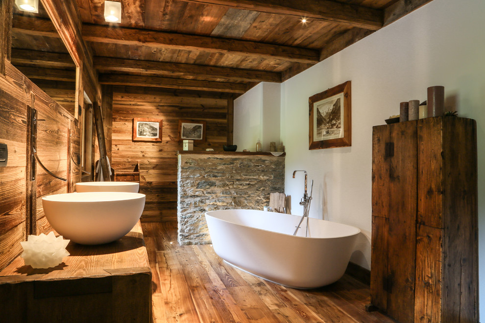 Idéer för att renovera ett stort rustikt brun brunt en-suite badrum, med släta luckor, ett fristående badkar, mellanmörkt trägolv, ett fristående handfat, skåp i mörkt trä, bruna väggar, träbänkskiva och brunt golv