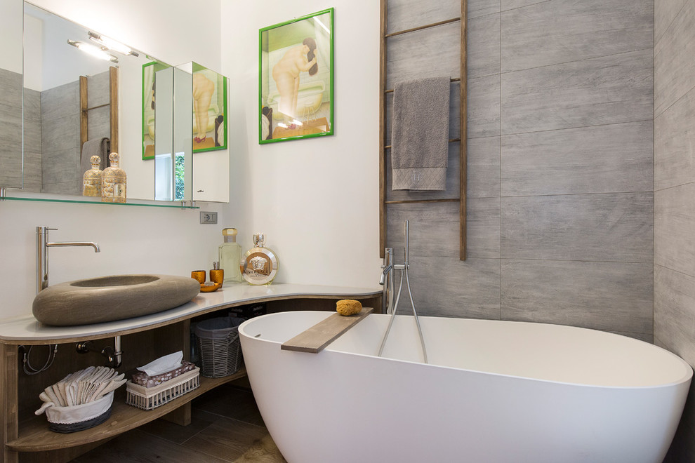 ミラノにある中くらいなアジアンスタイルのおしゃれなマスターバスルーム (オープンシェルフ、中間色木目調キャビネット、置き型浴槽、シャワー付き浴槽	、ベッセル式洗面器、オープンシャワー、グレーのタイル、白い壁) の写真