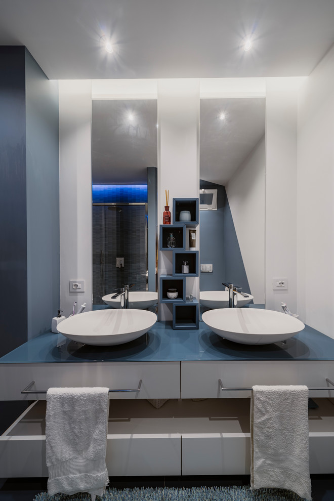 Idéer för små funkis blått badrum med dusch, med släta luckor, turkosa skåp, en dusch i en alkov, en toalettstol med separat cisternkåpa, blå kakel, porslinskakel, flerfärgade väggar, klinkergolv i porslin, ett fristående handfat, bänkskiva i glas, blått golv och dusch med skjutdörr