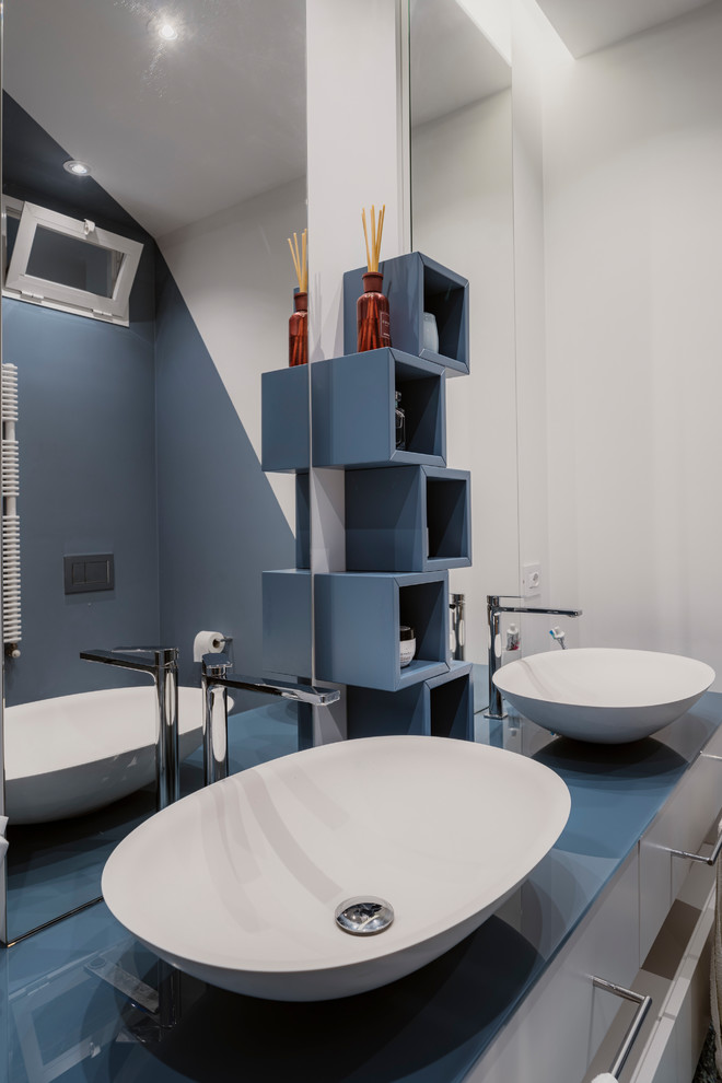 На фото: маленькая ванная комната в стиле модернизм с плоскими фасадами, бирюзовыми фасадами, душем в нише, раздельным унитазом, синей плиткой, керамогранитной плиткой, разноцветными стенами, полом из керамогранита, душевой кабиной, настольной раковиной, стеклянной столешницей, синим полом, душем с раздвижными дверями и синей столешницей для на участке и в саду