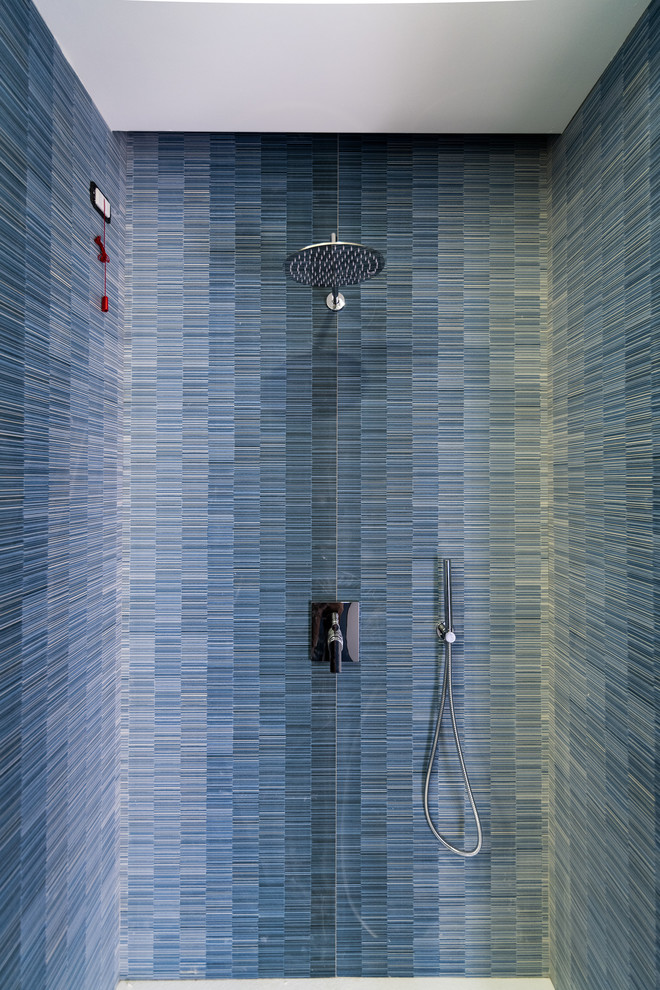 Идея дизайна: ванная комната среднего размера в стиле модернизм с плоскими фасадами, белыми фасадами, душем в нише, инсталляцией, разноцветной плиткой, керамогранитной плиткой, разноцветными стенами, полом из керамогранита, душевой кабиной, настольной раковиной, стеклянной столешницей, синим полом, душем с раздвижными дверями и бирюзовой столешницей