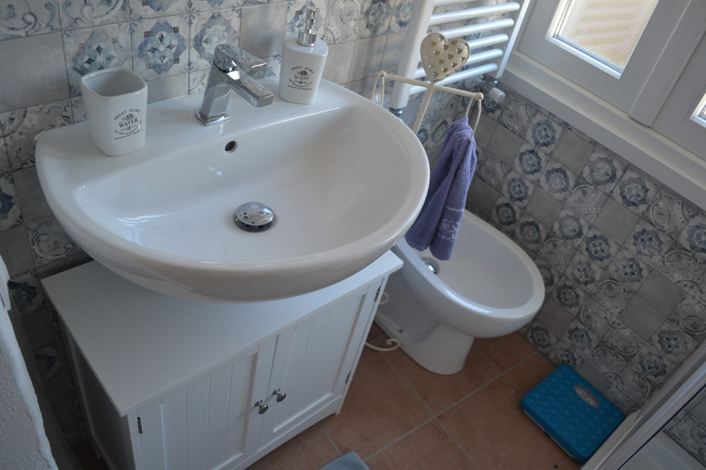 Photo of a small farmhouse shower room bathroom in Other with raised-panel cabinets, white cabinets, a corner shower, a two-piece toilet, multi-coloured tiles, porcelain tiles, multi-coloured walls, porcelain flooring, laminate worktops, a sliding door and white worktops.