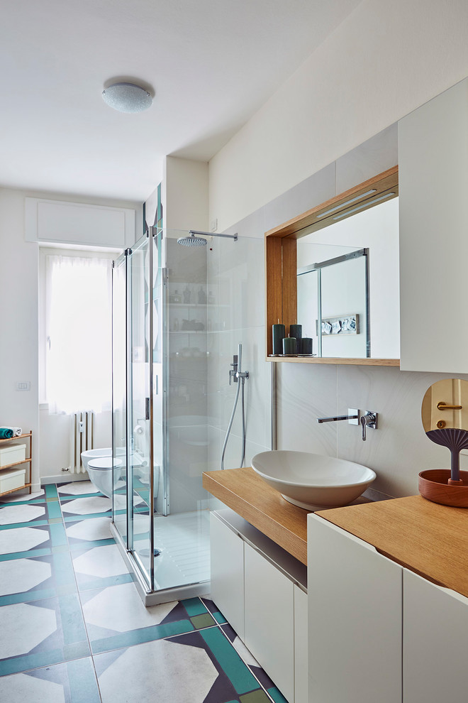 Example of a large trendy green tile ceramic tile and multicolored floor bathroom design in Milan with flat-panel cabinets, white cabinets, white walls, a vessel sink, wood countertops, a hinged shower door and brown countertops