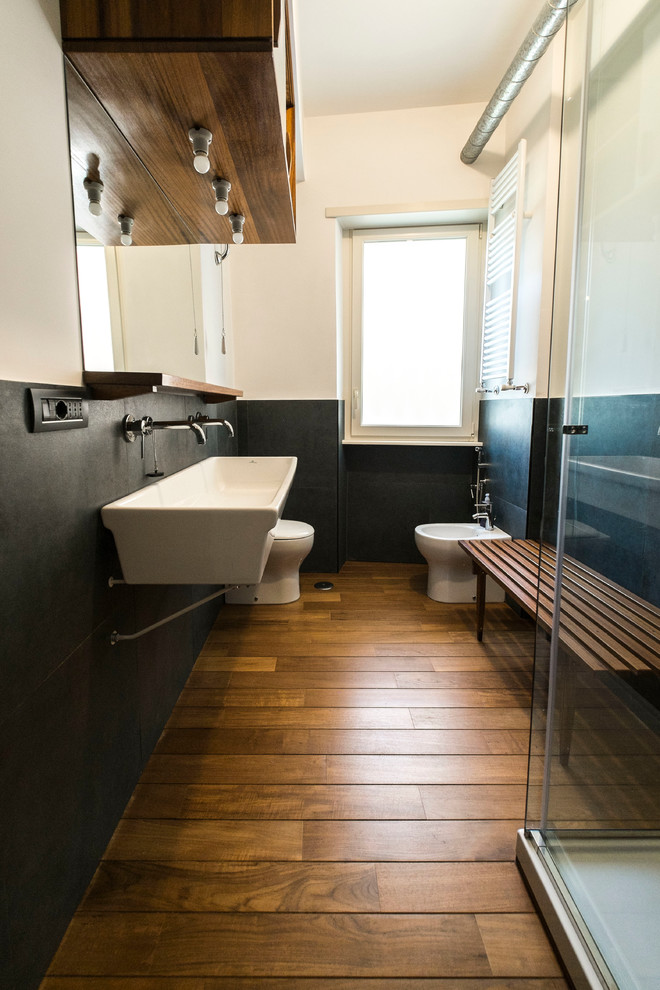 Пример оригинального дизайна: маленькая ванная комната в стиле ретро с плоскими фасадами, темными деревянными фасадами, двойным душем, раздельным унитазом, черной плиткой, керамогранитной плиткой, белыми стенами, паркетным полом среднего тона, душевой кабиной, подвесной раковиной и душем с раздвижными дверями для на участке и в саду