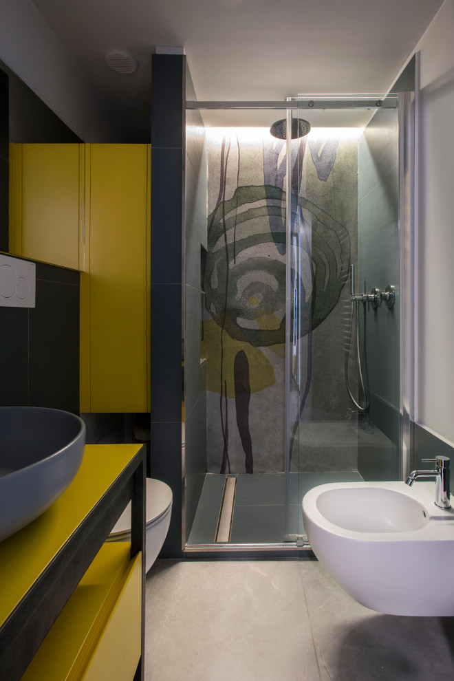 Пример оригинального дизайна: ванная комната в стиле фьюжн с фасадами островного типа, желтыми фасадами, инсталляцией, полом из керамогранита, настольной раковиной, серым полом и душем с раздвижными дверями
