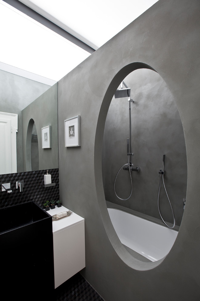 Источник вдохновения для домашнего уюта: главная ванная комната в современном стиле с плоскими фасадами, белыми фасадами, полновстраиваемой ванной, душем над ванной, серой плиткой, серыми стенами, черным полом и белой столешницей