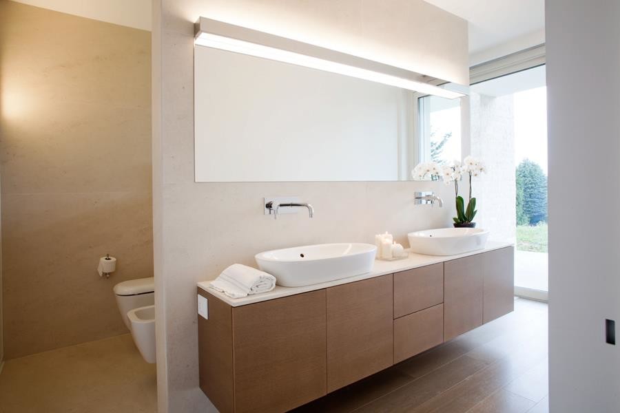 Design ideas for a large contemporary ensuite bathroom in Milan with flat-panel cabinets, light wood cabinets, an alcove bath, a walk-in shower, a wall mounted toilet, white walls, porcelain flooring, a vessel sink and solid surface worktops.