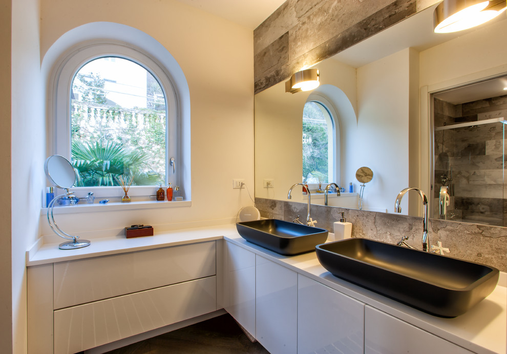 Cette image montre une salle de bain principale minimaliste de taille moyenne avec un placard à porte plane, des portes de placard blanches, un mur blanc et une vasque.