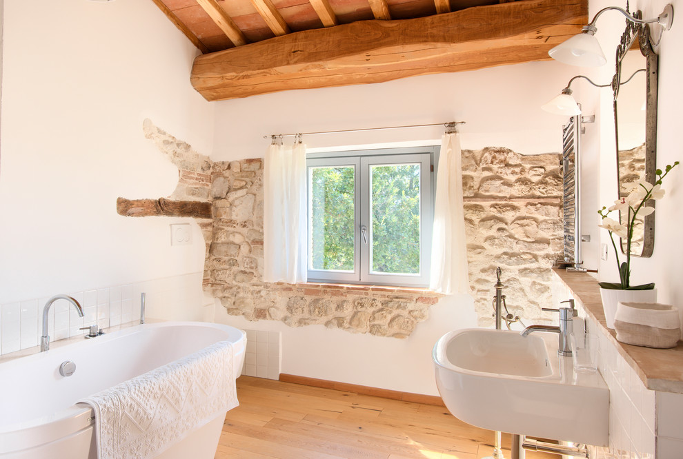 Esempio di una stanza da bagno padronale mediterranea con vasca freestanding, piastrelle bianche, pareti bianche, parquet chiaro, lavabo sospeso, un lavabo e soffitto in legno