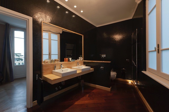 На фото: ванная комната в современном стиле с открытыми фасадами, душем в нише, раздельным унитазом, черной плиткой, стеклянной плиткой, черными стенами, темным паркетным полом, душевой кабиной, настольной раковиной и мраморной столешницей