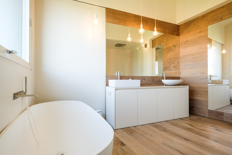 Photo of a contemporary ensuite bathroom in Milan with flat-panel cabinets, white cabinets, white walls, light hardwood flooring, a vessel sink and white worktops.