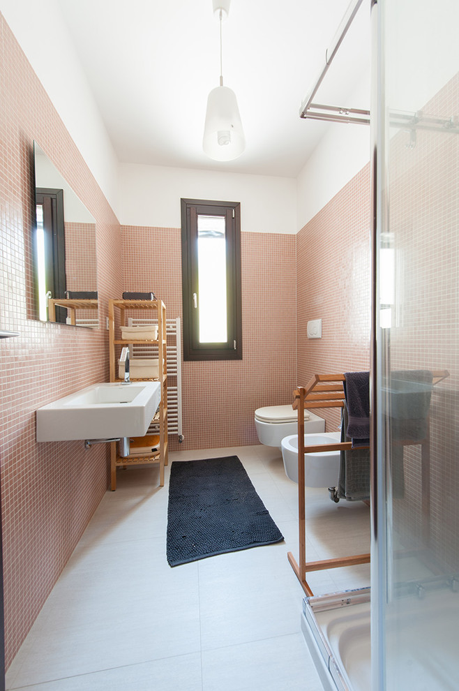 Cette photo montre une petite salle d'eau tendance avec un placard sans porte, une douche d'angle, WC suspendus, un carrelage orange, un carrelage rose, un mur orange, un lavabo suspendu, un sol blanc et une cabine de douche à porte coulissante.