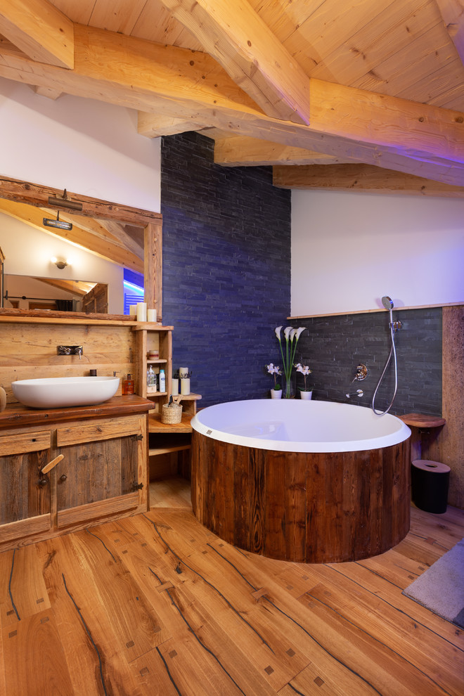 Idées déco pour une salle de bain principale montagne en bois foncé avec un bain bouillonnant, un plan de toilette en bois, un mur blanc, un sol en bois brun, une vasque, un sol marron et un plan de toilette marron.