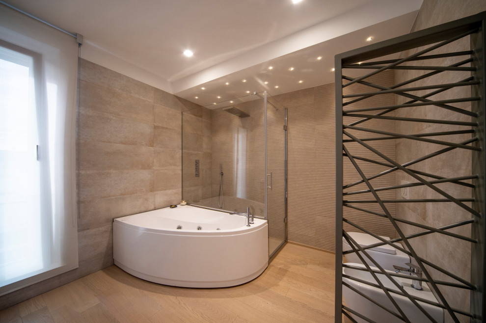 Modern inredning av ett stort badrum, med grå skåp, ett hörnbadkar, en dusch/badkar-kombination, porslinskakel, ljust trägolv, brunt golv och dusch med gångjärnsdörr