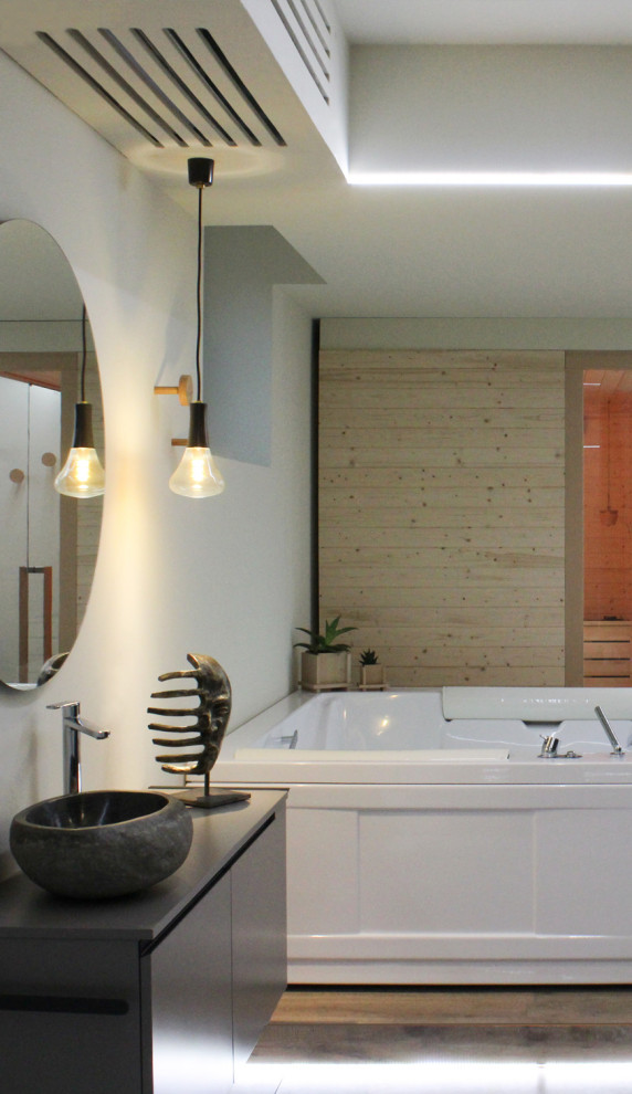 Cette photo montre un grand sauna moderne avec un bain bouillonnant, un mur beige, parquet clair et un plafond décaissé.