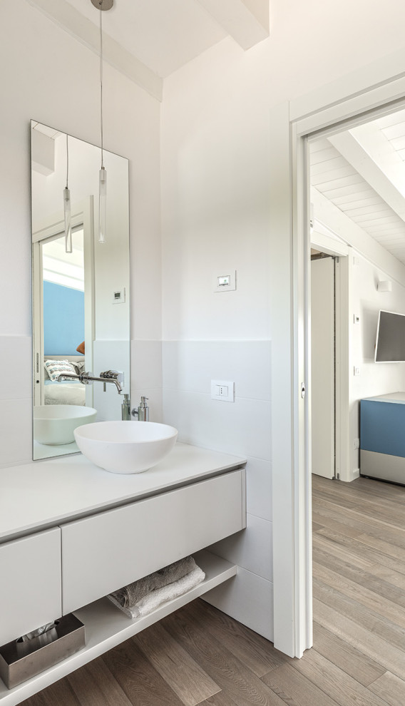 Foto på ett mellanstort maritimt vit en-suite badrum, med släta luckor, vita skåp, vita väggar, mörkt trägolv, ett fristående handfat, laminatbänkskiva och flerfärgat golv