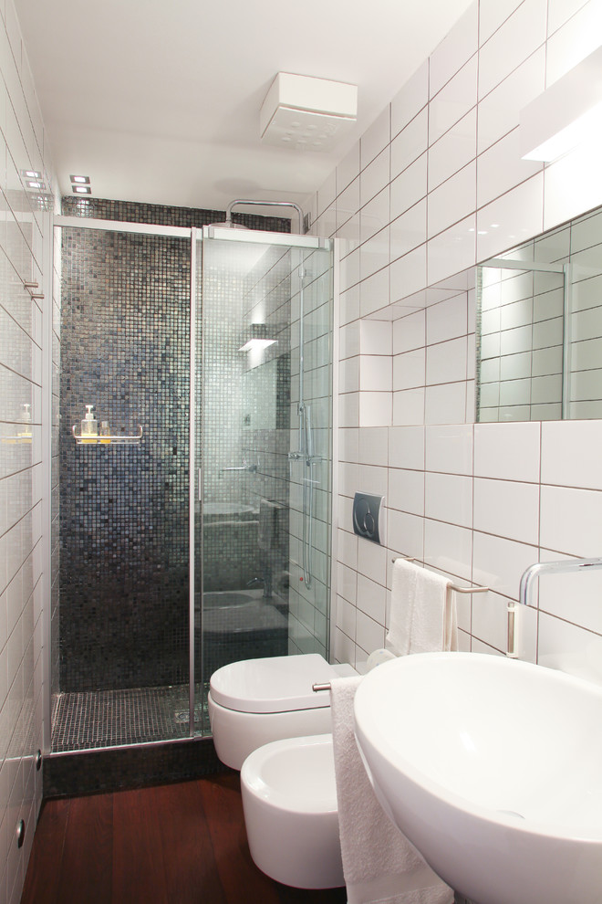 Modern inredning av ett litet badrum med dusch, med en dusch i en alkov, en toalettstol med hel cisternkåpa, vit kakel och keramikplattor