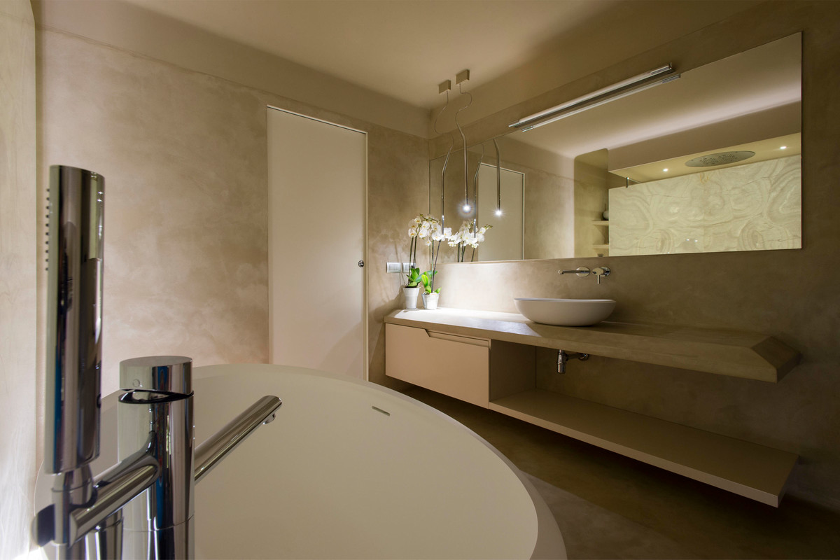 Inredning av ett modernt stort badrum, med en toalettstol med separat cisternkåpa, betonggolv, ett fristående handfat, beiget golv, beige kakel, ett fristående badkar, en kantlös dusch och med dusch som är öppen