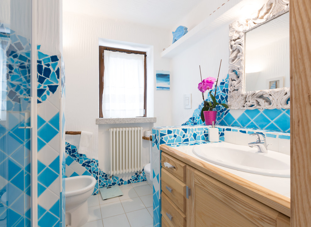 Idee per una stanza da bagno mediterranea con ante con riquadro incassato, ante in legno scuro, piastrelle blu, pareti bianche, lavabo da incasso, top piastrellato e pavimento bianco