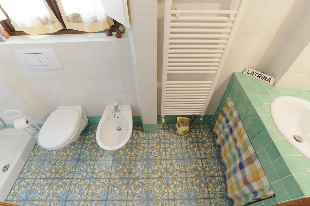 Diseño de cuarto de baño clásico con sanitario de pared, baldosas y/o azulejos verdes, baldosas y/o azulejos de cerámica, paredes blancas, suelo de baldosas de cerámica y armarios abiertos