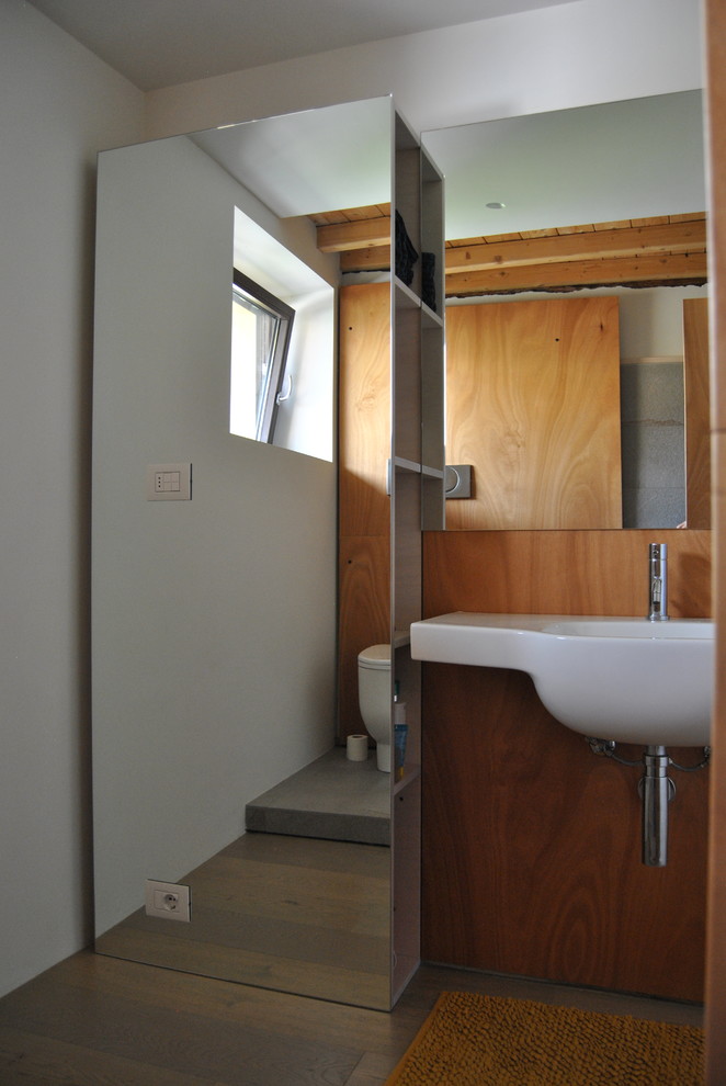 Inspiration för små moderna badrum med dusch, med luckor med glaspanel, en hörndusch, en toalettstol med separat cisternkåpa, vita väggar, ljust trägolv, ett väggmonterat handfat, beiget golv och dusch med duschdraperi