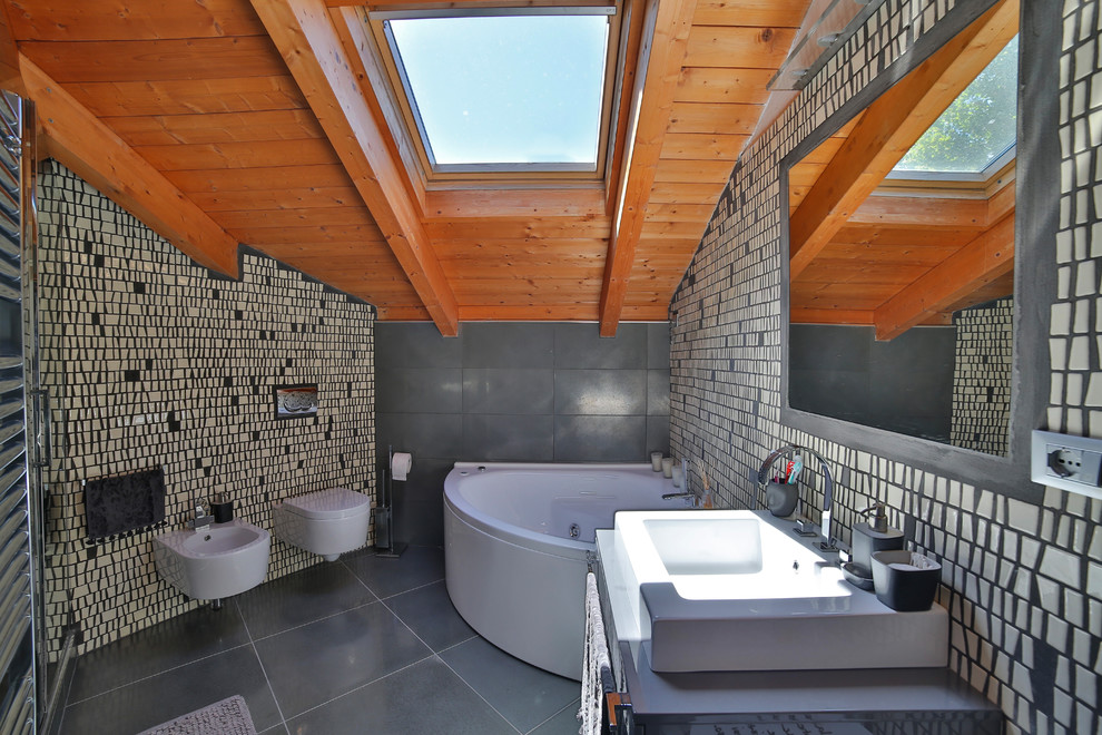 Réalisation d'une salle de bain principale minimaliste avec un bain bouillonnant, WC suspendus, un mur gris et une grande vasque.