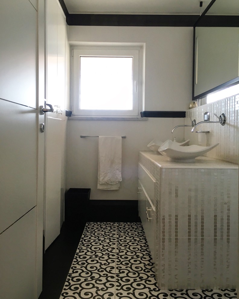 Пример оригинального дизайна: главная ванная комната среднего размера в современном стиле с плоскими фасадами, белыми фасадами, раздельным унитазом, черно-белой плиткой, керамогранитной плиткой, белыми стенами, полом из керамогранита, настольной раковиной, столешницей из плитки и разноцветным полом